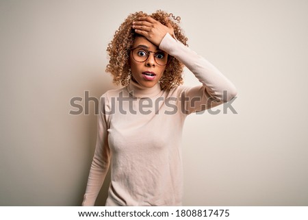 Young african american woman wearing turtleneck sweater and glasses over white background surprised with hand on head for mistake, remember error. Forgot, bad memory concept.