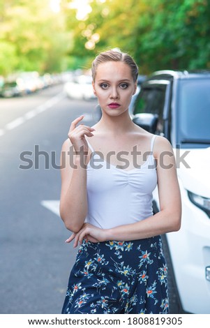 Portrait of a beautiful young girl on the street near the car