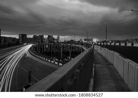 Long Exposure of the speed of traffic light trails at night under a steel bridge in the city. Chelyabinsk, Russia.