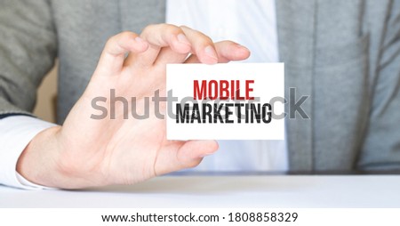 businessman holding a card with text MOBILE MARKETING