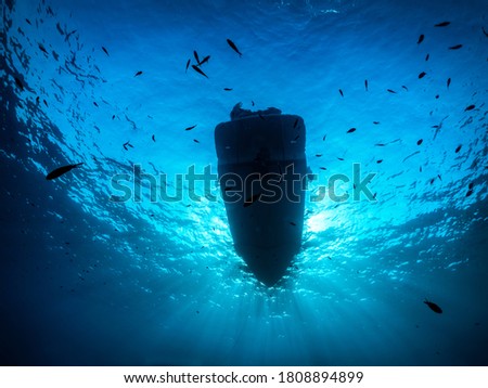 Underwater view of a anchored diving boat against sunlight