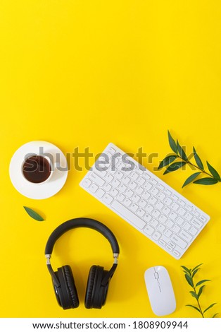 Yellow desktop with wireless headphones, laptop, mouse, cup of cofffe and plats top view. Music concept