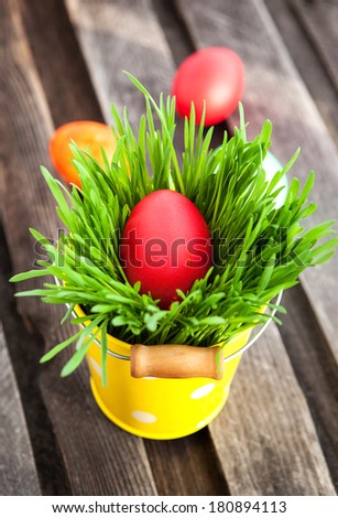 Colorful painted Easter egg on a fresh green grass in yellow bucket
