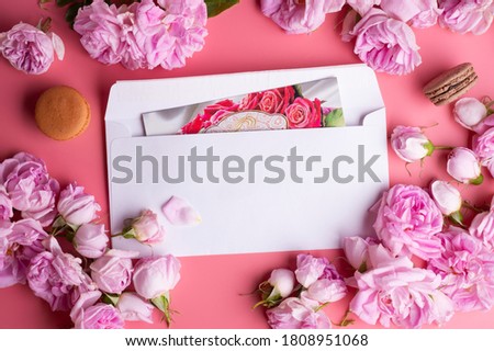 pink roses with white envelope and macaroons around pink background. life style concept