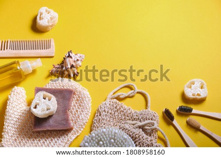 Zero waste bathroom accessories, bath set made of natural materials, soap, washcloths, loofah, body oil, massager brush, bamboo toothbrushes on a yellow background, copy place