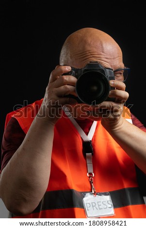 Senior man photographer shooting with a dslr camera. black background. Press accredited.