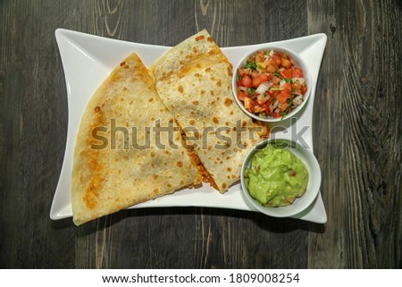 Top view of a chicken tinga quesadilla with pico de gallo and guacamole on the side.