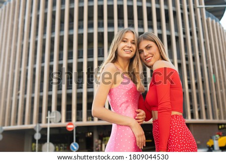 Two women friends laughing with a perfect white teeth. Blurred background.