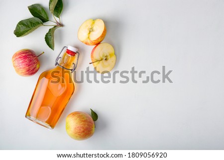 Fresh ripe apples and apple cider vinegar. Apple cider in a glass bottle and fresh apples. Light background. Top view. Copy space of your text.