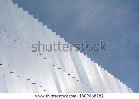 the modern facade of the building is made of white metal against a cloudy sky. Diagonal image. Concept-abstract background