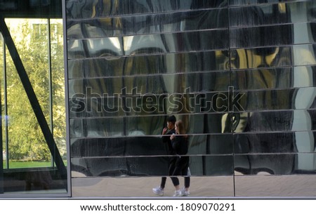 In the glass wall of a modern shopping center, broken reflections of people. Concept-modern life breaks a person