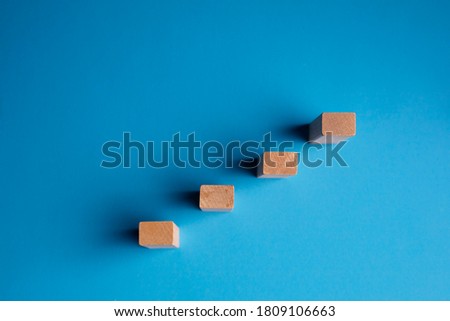 Wooden pegs placed in a stairway structure on blue background Royalty-Free Stock Photo #1809106663