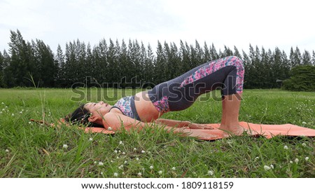 A woman wearing exercise clothes playing yoga on the mat afternoon at the park.