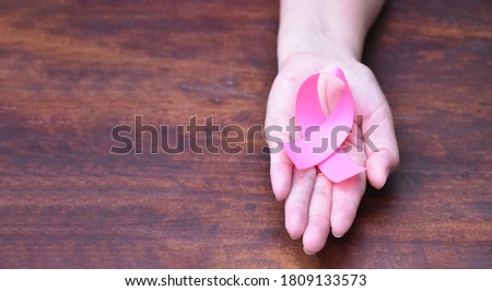 The pink ribbon in hand, a symbol of the global women's breast cancer campaign.