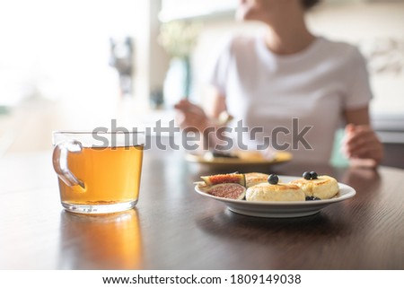Having tasty breakfast with tea and cheese pancakes dessert (selective focus)