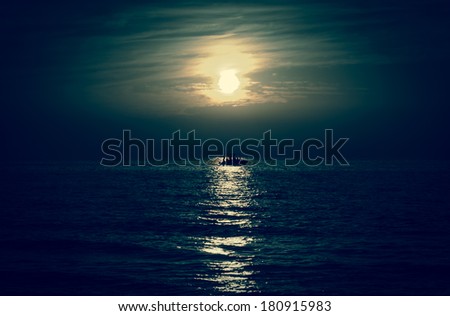 Silhouette of the fisherman or leisure boat sailing toward the moon. 