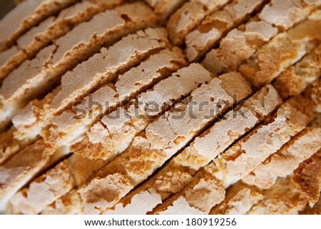 Over head close up detail view of a fresh and organic loaf of white bread sliced in multiple segments. Baked foods, background texture.