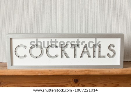 Light up sign saying cocktails on a wooden shelf