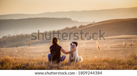 woman with dog relaxing in autumn landscape