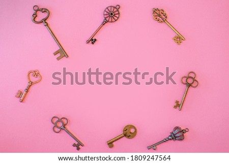 Many different old keys from different locks, scattered chaotically, flat lay. Finding the right key, encryption, concept. Retro vintage copper keys on a pink background, copy space in the center