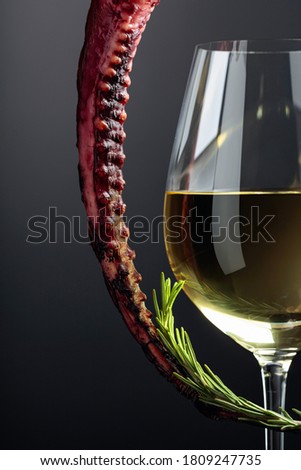 Grilled octopus and white wine glass on a black background. Copy space.