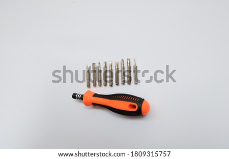 The handle of the screwdriver is a combination of orange, black and seven different types of screwdrivers. Isolated on white background.