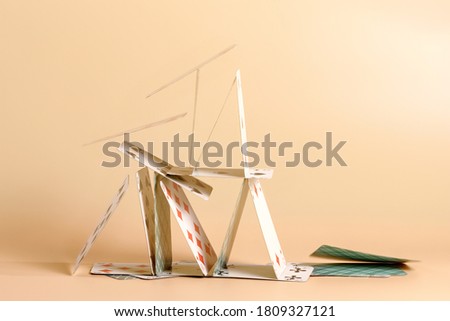 Crashed house of cards. Falling cards on beige background
