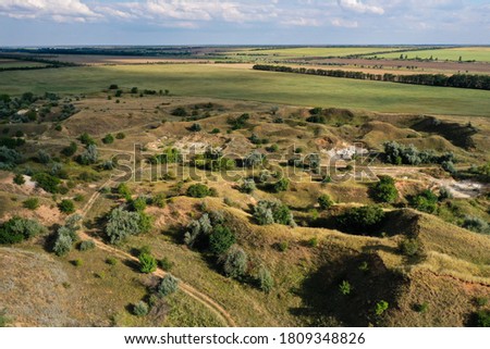 Aerial panorama of hilly area near agricultural fields during sunny summer day, Ukrainian countryside.