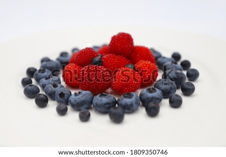 Various berries with white background. Raspberries in centre, bluberries and blackberries around. Close up, texture, lightbox.