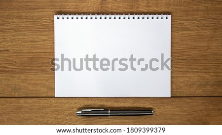White notebook and pen on wood table. Business and education concept. Copy space.