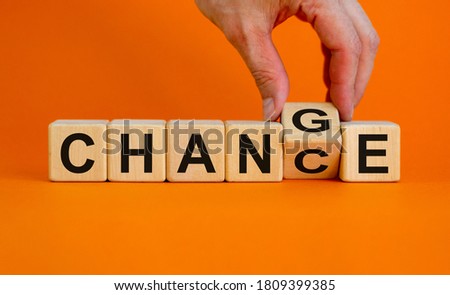 Hand flips a cube and changes the word 'change' to 'chance'. Beautiful orange background, copy space. Business concept.
