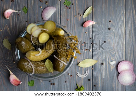 Pickled gherkins or cucumbers in a glass bowl on a wooden rustic table with space for text. View from above. Royalty-Free Stock Photo #1809402370