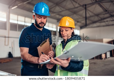 Factory worker signing document in industrial hall