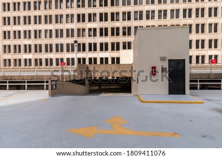 View of Exit Ramp in Empty Rooftop Garage with Large Building on the Background