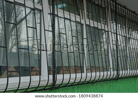 white window with black iron bars on a green wall outside