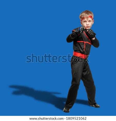 Young boy taekwondo fighter attacking opponent on blue background