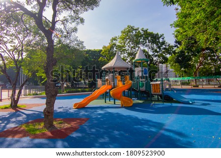 Colorful children playground activities in public park surrounded by green trees 