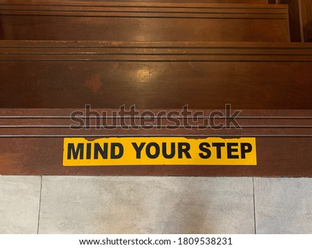 Mind your step sticker on floor over the staircase. Warning and safety concept.