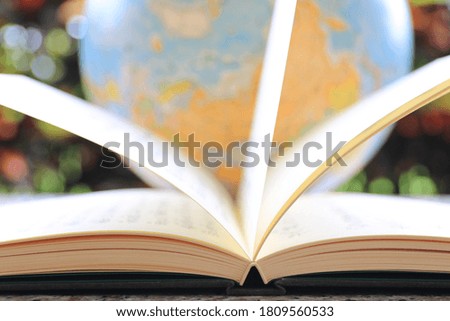 Backlit images of open books on the table Globe as background selective focus and shallow depth of field