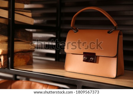 Stylish woman's bag on shelf in boutique