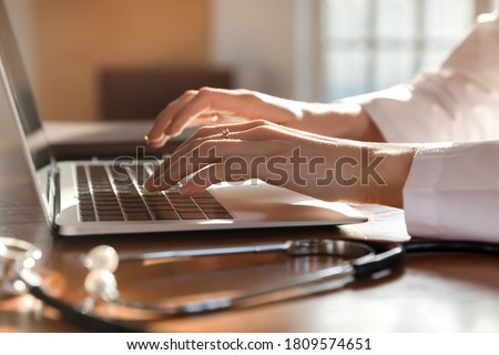 Close up woman doctor working on laptop, typing on keyboard, therapist physician nurse sitting at work table in hospital office, using medical apps, consulting online, writing report Royalty-Free Stock Photo #1809574651