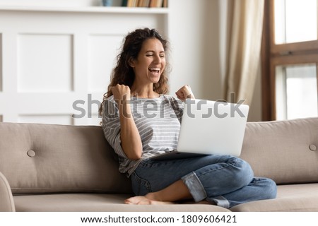 Woman sit on sofa put pc on lap clenched fists scream with joy while read great news on laptop. Gambler celebrate online auction bet victory. Got incredible offer sincere emotions of happiness concept Royalty-Free Stock Photo #1809606421
