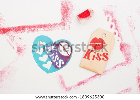 stencil stamping of the word kiss on wooden label. Red paint. Romantic message. Valentine's Day.