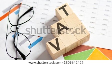 VAT words with wooden blocks on chart background. Business concept.