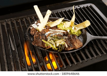 Sirloin fillet with beans, guacamole and chili served on a grill with fire.