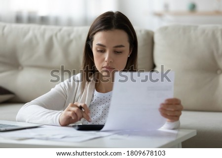 Head shot focused young lady holding banking mortgage payment notification, managing household budget alone at home. Serious woman calculating incomes outcomes earnings expenditures indoors. Royalty-Free Stock Photo #1809678103