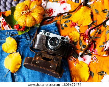 Top view of vintage photo camera, yellow sweater, knitted blanket and pumpkin, fall leaves. Happy thanksgiving autumn background