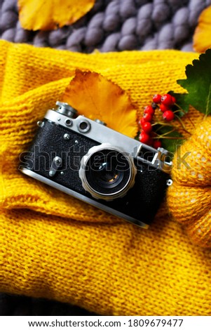 Top view of vintage photo camera, yellow sweater, knitted blanket and pumpkin, fall leaves. Happy thanksgiving autumn background