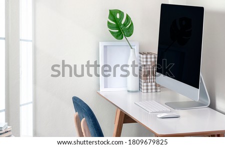 Home office concept. Home office desk with desktop computer in modern room. Mockup monitor with keyboard, mouse and houseplant on the table in white room.