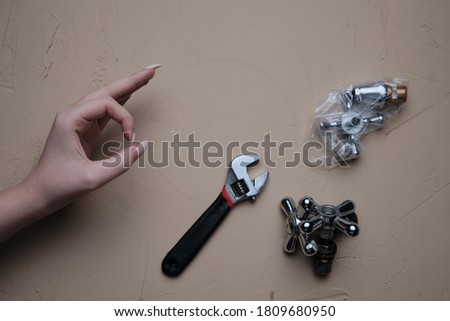 Girl hand showing OK sign with a table full of plumbing tools and partsch. Tool for plumbing repair with their hands